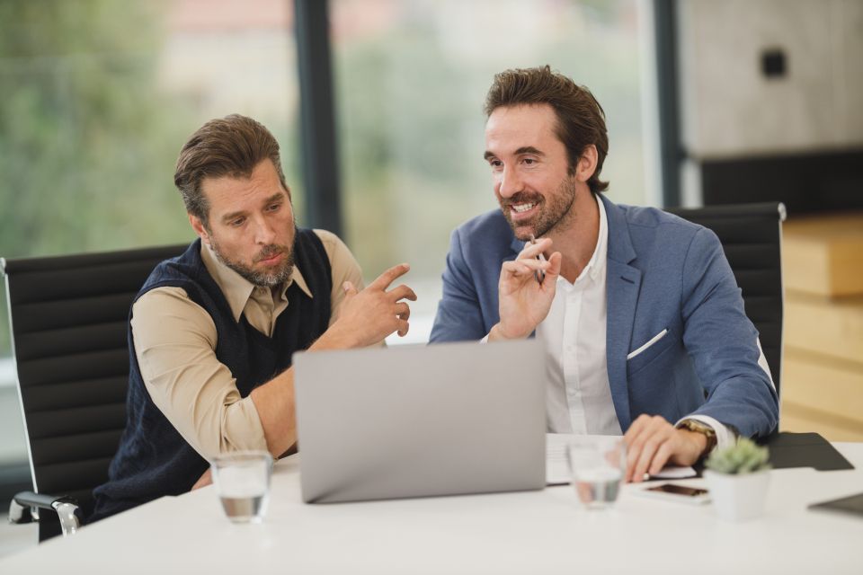 Dos profesionales revisando reportes en una laptop durante una reunión de oficina